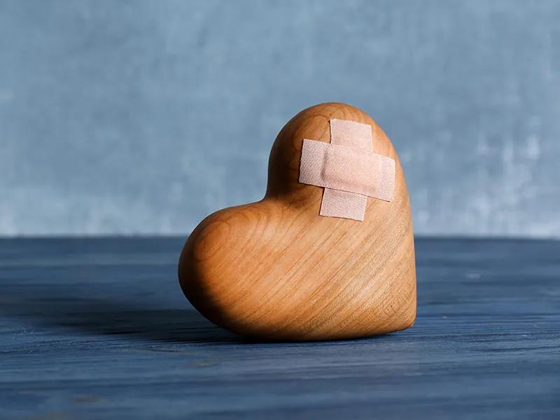A wooden heart with a plaster on it